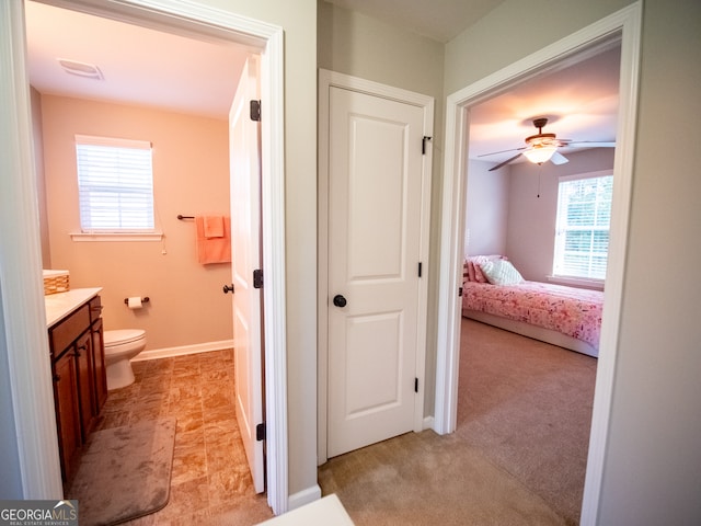 bathroom with vanity, toilet, ceiling fan, and a healthy amount of sunlight