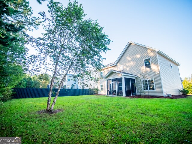 rear view of house featuring a lawn and a sunroom