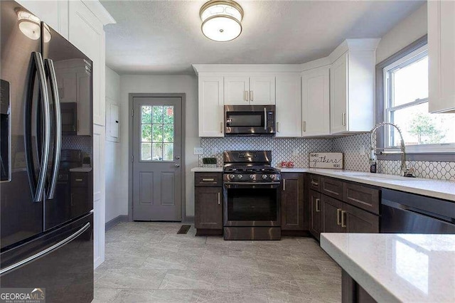 kitchen featuring stainless steel appliances, tasteful backsplash, sink, and white cabinetry