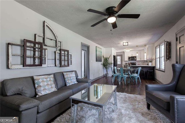 living room with hardwood / wood-style flooring, ceiling fan, and a textured ceiling