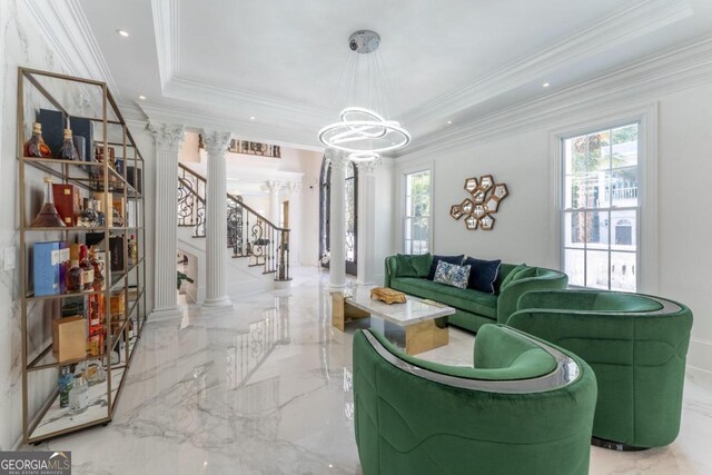 living room with decorative columns, crown molding, and a tray ceiling