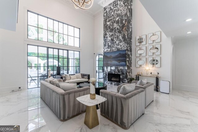 living room with a high ceiling, a high end fireplace, and crown molding