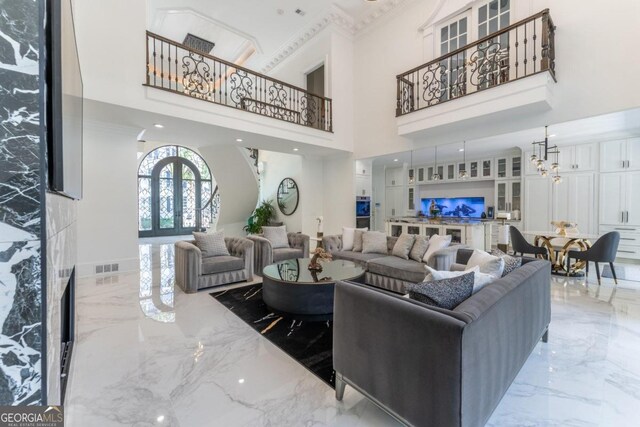 living room featuring a towering ceiling, french doors, ornamental molding, and a notable chandelier