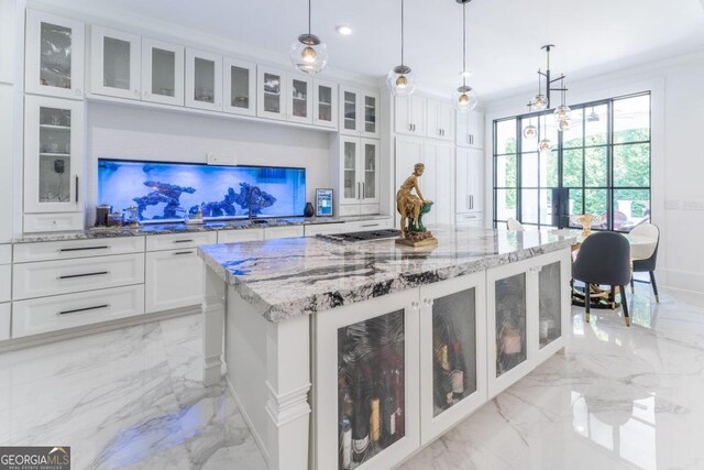 kitchen featuring light stone counters, hanging light fixtures, a center island, and white cabinets