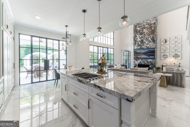 kitchen featuring a center island, white cabinets, a premium fireplace, pendant lighting, and stainless steel gas cooktop