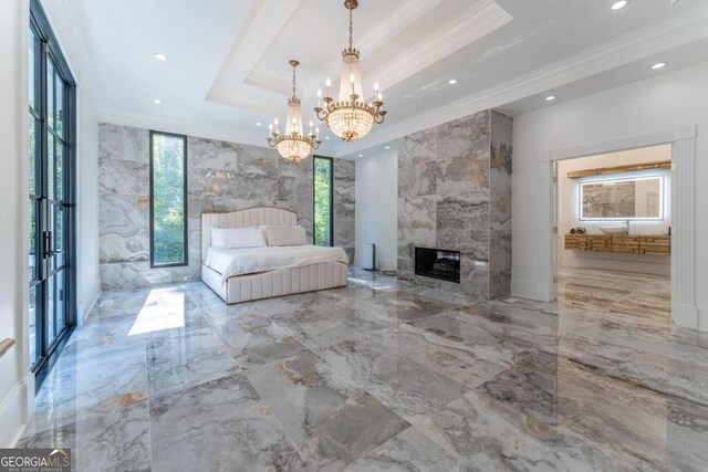 unfurnished bedroom with tile walls, a high end fireplace, a tray ceiling, an inviting chandelier, and ornamental molding