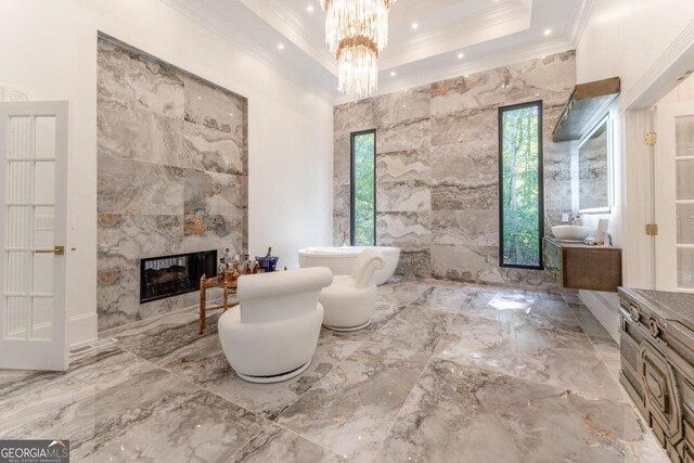 bathroom with crown molding, a bath, tile walls, a fireplace, and vanity