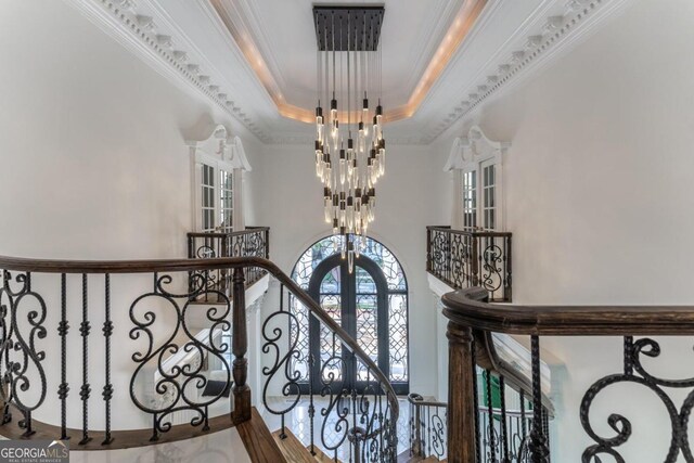 interior space featuring french doors, wood-type flooring, a chandelier, a tray ceiling, and crown molding