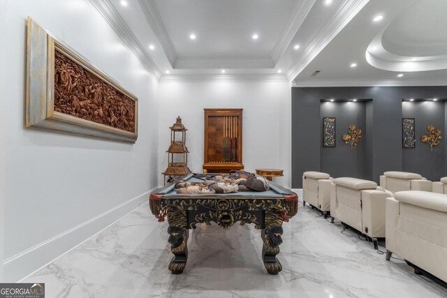 recreation room featuring a raised ceiling and ornamental molding