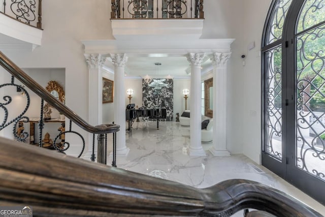 foyer entrance featuring french doors, crown molding, and ornate columns