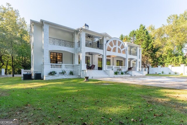 back of property with a yard, ceiling fan, a balcony, covered porch, and central AC