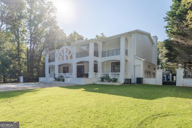 view of front of home with a balcony, a front lawn, and central air condition unit