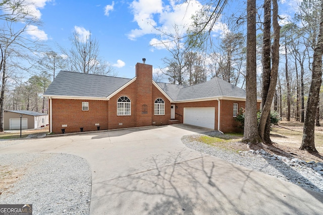 view of front of home with brick siding, driveway, a chimney, and an attached garage