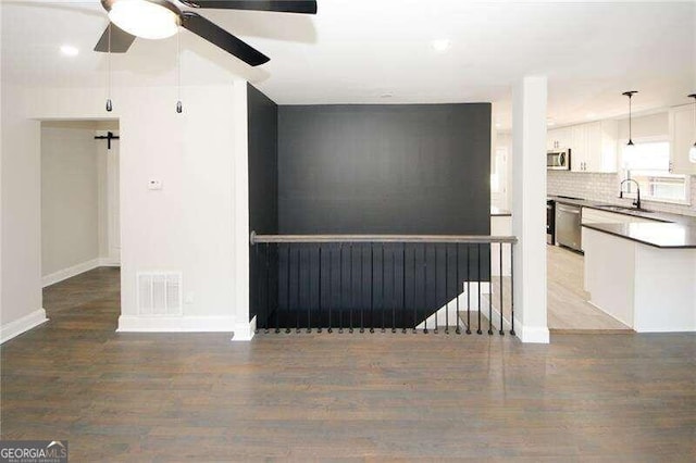 unfurnished living room with wood-type flooring, sink, and ceiling fan