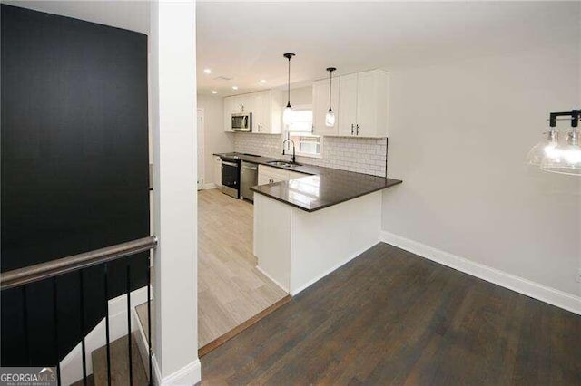 kitchen featuring hardwood / wood-style flooring, decorative light fixtures, stainless steel appliances, and white cabinets