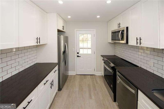 kitchen featuring white cabinets, stainless steel appliances, light wood-type flooring, and decorative backsplash