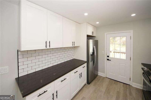 kitchen with stainless steel appliances, backsplash, light wood-type flooring, and white cabinetry