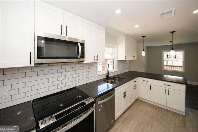 kitchen with white cabinets, appliances with stainless steel finishes, light wood-type flooring, and a healthy amount of sunlight