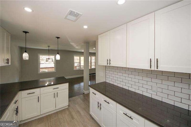 kitchen with decorative light fixtures, backsplash, light hardwood / wood-style floors, and white cabinetry