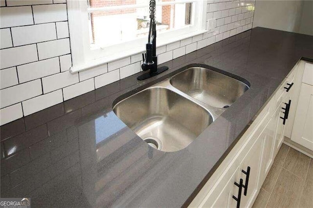 details with white cabinets, dark stone counters, sink, and decorative backsplash