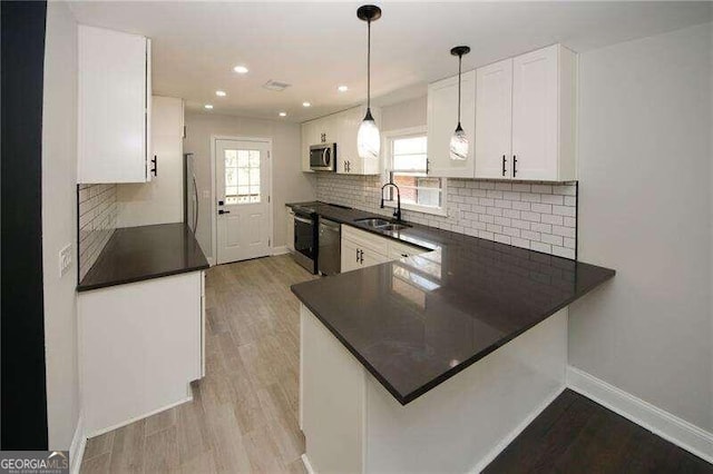 kitchen featuring appliances with stainless steel finishes, a healthy amount of sunlight, white cabinetry, and sink