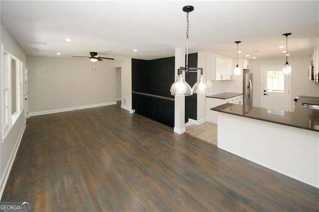 kitchen with white cabinets, stainless steel refrigerator, pendant lighting, and dark wood-type flooring