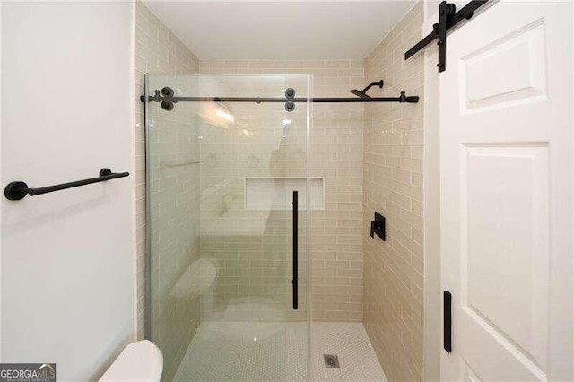 bathroom with a shower with shower door and toilet