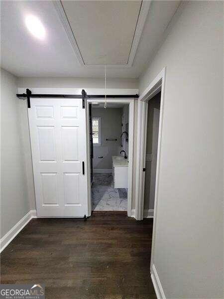 hallway featuring a barn door and dark hardwood / wood-style flooring