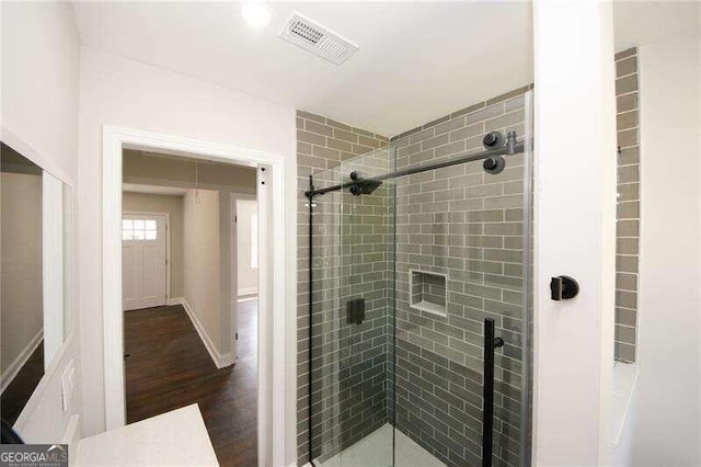 bathroom with hardwood / wood-style flooring and a shower with door