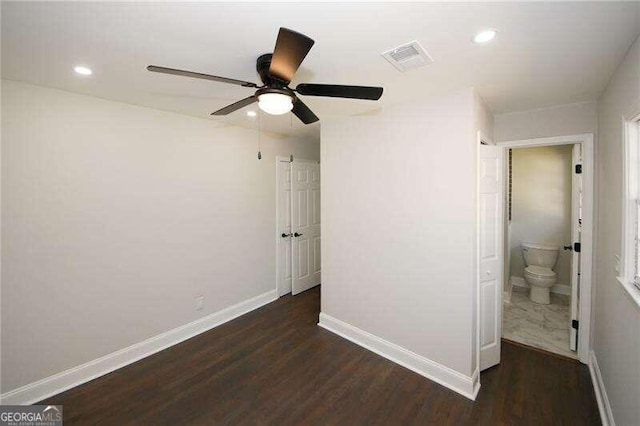 interior space with ensuite bath, dark hardwood / wood-style flooring, and ceiling fan