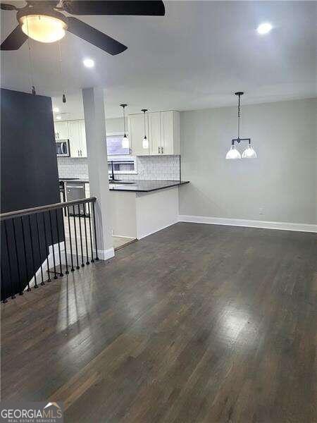 interior space featuring dark hardwood / wood-style floors, decorative light fixtures, backsplash, and white cabinetry