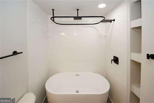 bathroom featuring a bathing tub, tile walls, and toilet