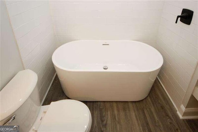 bathroom with wood-type flooring, a bathing tub, and toilet