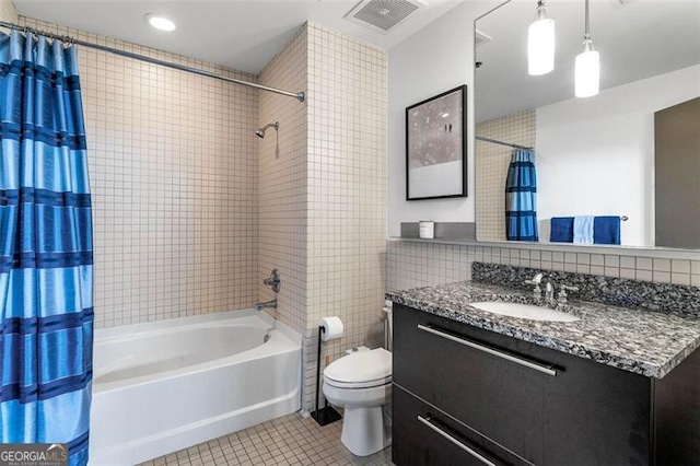 full bathroom with shower / tub combo with curtain, vanity, tile walls, tile patterned flooring, and toilet