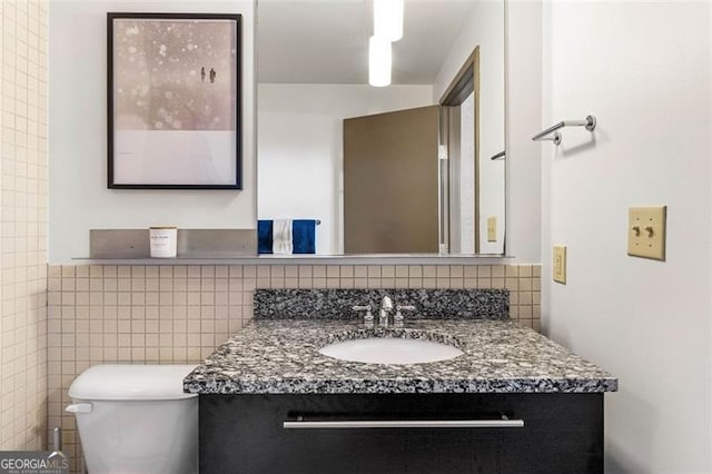 bathroom featuring toilet, tile walls, and vanity