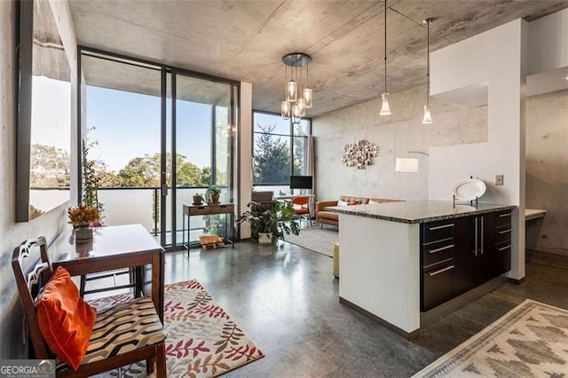 kitchen with an inviting chandelier, stone countertops, a wall of windows, dark brown cabinets, and decorative light fixtures