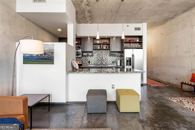 kitchen featuring dark stone counters, hanging light fixtures, appliances with stainless steel finishes, and white cabinetry