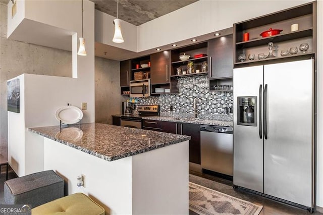 kitchen with tasteful backsplash, dark stone countertops, hanging light fixtures, appliances with stainless steel finishes, and a kitchen bar