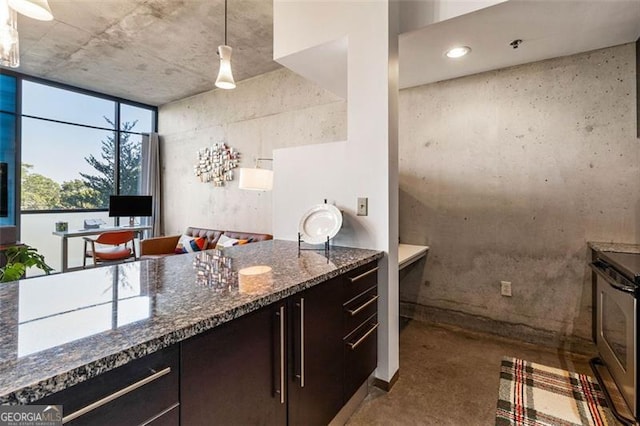 kitchen with dark brown cabinetry, hanging light fixtures, concrete flooring, stainless steel stove, and dark stone countertops