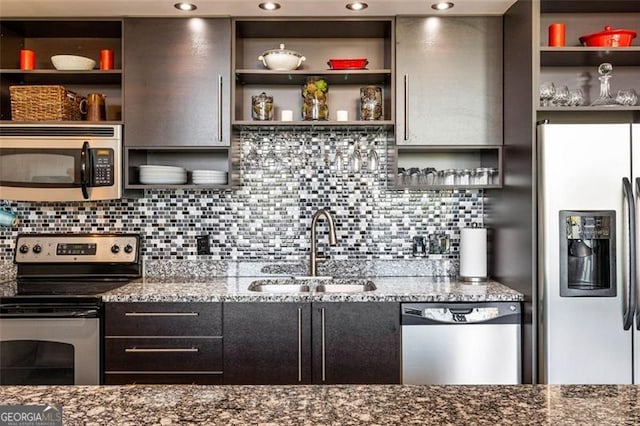 kitchen with stainless steel appliances, backsplash, sink, and light stone counters