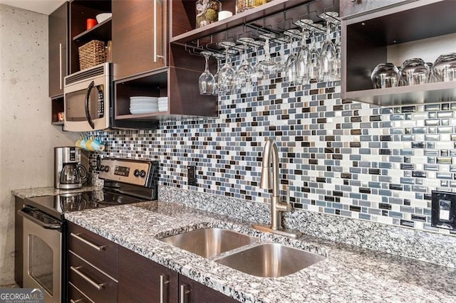 kitchen with appliances with stainless steel finishes, light stone counters, decorative backsplash, and sink