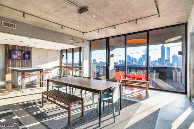 dining room with plenty of natural light, a wall of windows, and concrete flooring