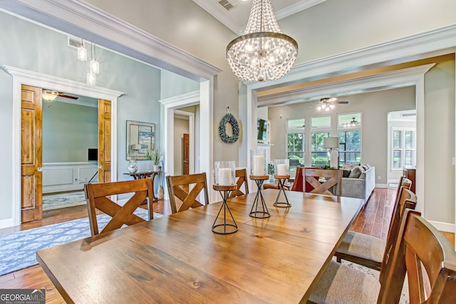 dining room with ceiling fan with notable chandelier, crown molding, and hardwood / wood-style floors