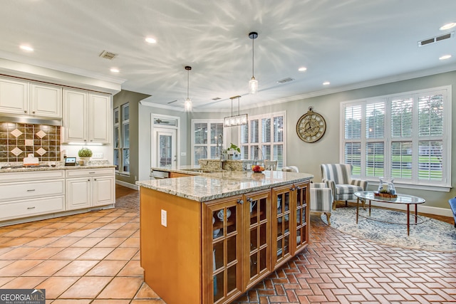 kitchen with ornamental molding, a kitchen island, decorative light fixtures, appliances with stainless steel finishes, and decorative backsplash