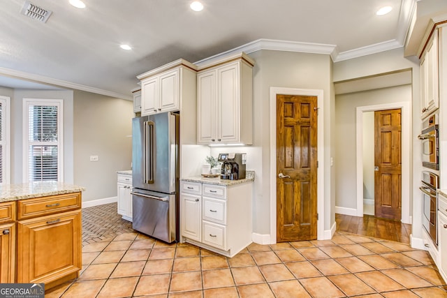 kitchen featuring light tile patterned flooring, light stone counters, crown molding, and stainless steel appliances