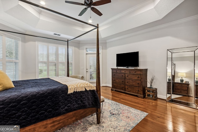 bedroom featuring ceiling fan, a raised ceiling, crown molding, and hardwood / wood-style floors