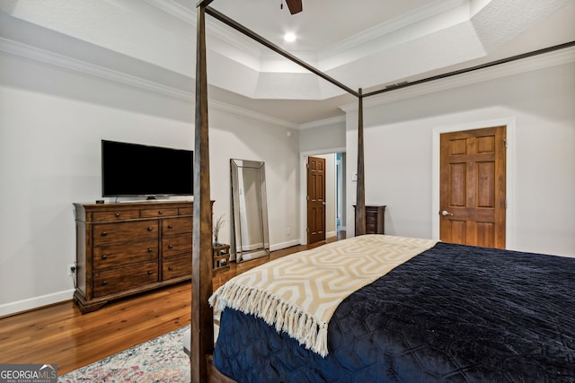 bedroom with a raised ceiling, ornamental molding, hardwood / wood-style flooring, and ceiling fan