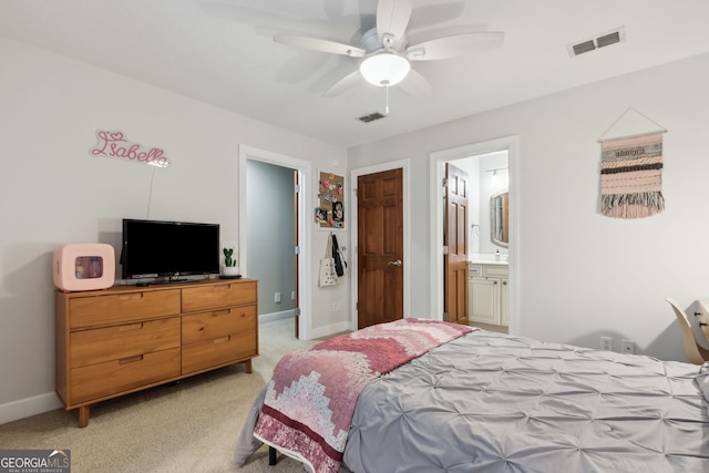 bedroom with ceiling fan, ensuite bath, and light colored carpet