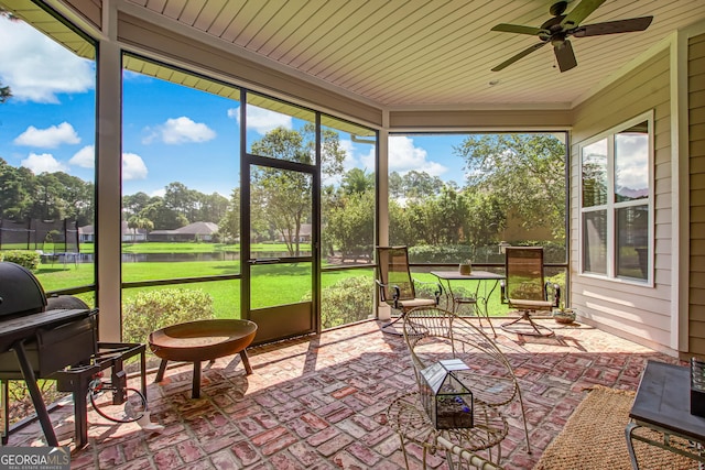 sunroom / solarium featuring plenty of natural light, wood ceiling, and ceiling fan