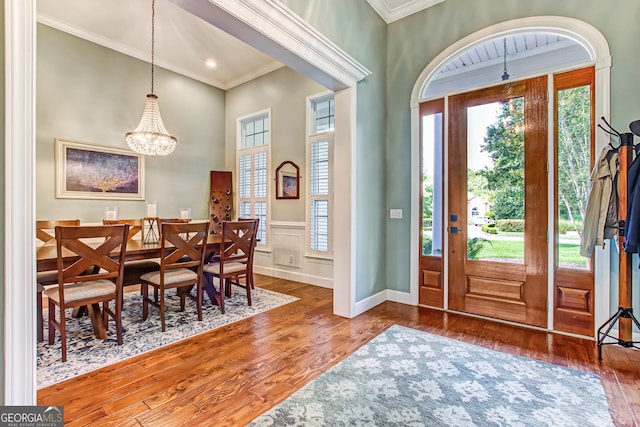 foyer with hardwood / wood-style flooring, crown molding, and an inviting chandelier